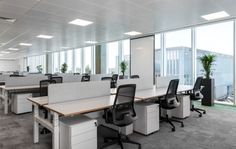 an empty office with desks and chairs in the middle of it, overlooking large windows