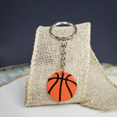 an orange basketball keychain sitting on top of a burlap bag with a chain hanging from it