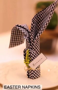 a napkin wrapped in black and white checks sits on a plate with a place card