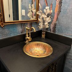 a bathroom sink sitting under a mirror next to a wooden counter top with flowers on it