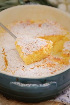 there is a piece of cake in the bowl with a knife inside it and powdered sugar on top