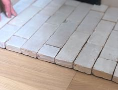 a person standing on top of a wooden floor next to a white tile countertop