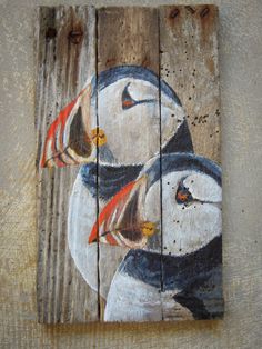 a painting of three birds on wood with one bird painted on it's face