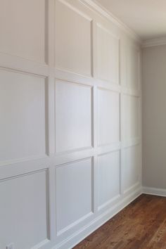 an empty room with white paneling on the walls and hard wood floors in it