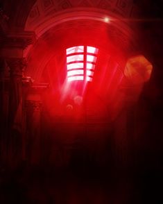 a red light shines brightly in the middle of a room with columns and arches