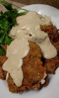 a white plate topped with fried chicken covered in gravy