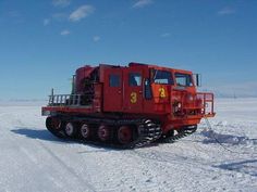 a red truck driving across snow covered ground