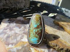 This is a huge piece of vintage Turquoise.  It is a light blue with almost a bit of green tint to it.   It also has a beautiful matrix in the stone. Freeform in shape and is a one of a kind statement ring.  Alan set this in a flat silver bezel and added a silver wire around the stone.   He then added a medium split double half round silver band on the back.  This is such an eye catching color when you wear it.   This is a perfect looking turquoise that you will have for many many years to come.  Handmade in our studio in Sandy Oregon. Hallmark:  HA 1854 Size 7 3/4       * we are unable to re-size this ring as it is a one of a kind piece. It is said that turquoise can relax your mind and calm emotions. Vintage Turquoise, Eye Catching Colors, Bohemian Jewelry, Silver Wire, Silver Band, Turquoise Ring, Metal Working, Boho Chic, Statement Rings