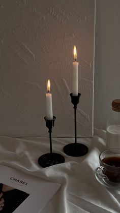 three lit candles sitting on top of a table next to a cup of coffee and a book