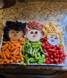 an assortment of fruits and vegetables arranged on a tray with the faces of people made out of them