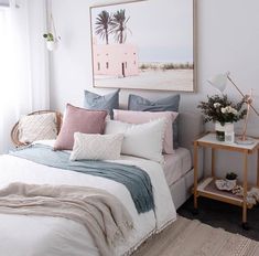 a bed with white sheets and pillows in a bedroom next to a painting on the wall