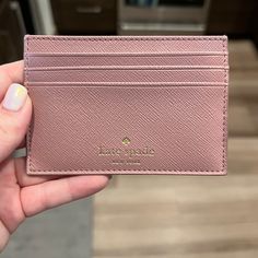 a person holding a pink card case in their hand