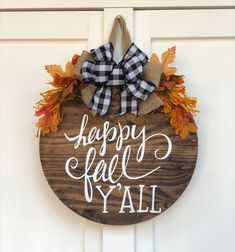 a wooden sign that says happy fall y'all hanging on a door with a bow