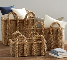 four woven baskets with white pillows and blue throw pillows on the floor next to each other