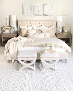 a bedroom with white bedding and pillows on the headboard, footstools and tables