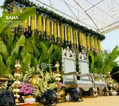 an elaborately decorated room with chairs and flowers on the wall, surrounded by greenery