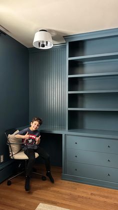 a man sitting in a chair next to a book shelf