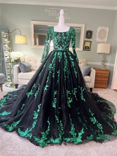 a black and green ball gown on display in a room with white carpeted flooring