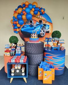 a car themed birthday party with orange and blue balloons on the top of a giant tire