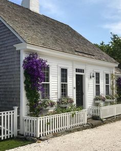 a white house with purple flowers on the windows