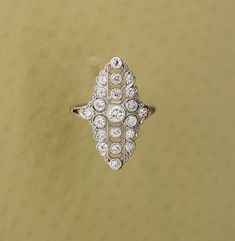 an antique diamond ring is displayed on a table with a yellow wall in the background