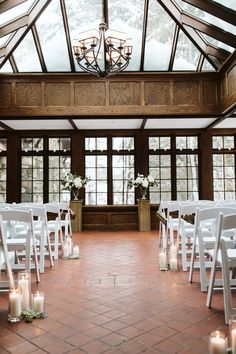 an indoor wedding venue with white chairs and candles