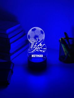 a night light with a soccer ball on it next to some books and pen holders