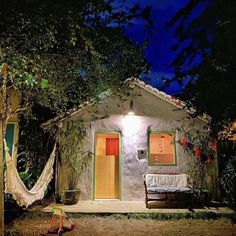 a small house with a hammock hanging from it's roof and door