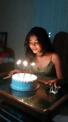 a woman sitting in front of a cake with lit candles