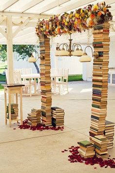 a bunch of books stacked on top of each other under a white tent covered in flowers