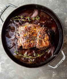 pork chops in a pot with sauce and herbs on the side, ready to be cooked