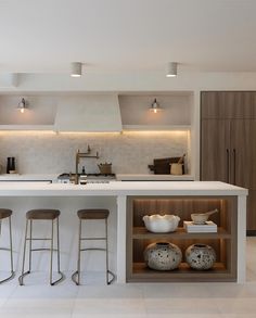 a kitchen with an island and stools in the center, surrounded by white tile flooring