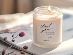 a white candle sitting on top of a table next to a notepad and flowers