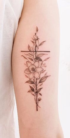 a cross and flowers tattoo on the arm