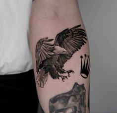 an eagle with a crown on it's arm next to a black and white tattoo