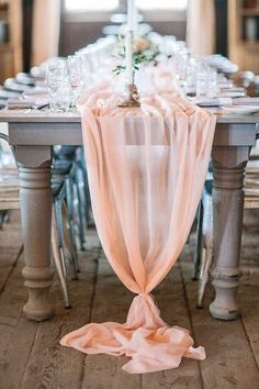 the table is set with silver chairs and an orange scarf draped over it's edge