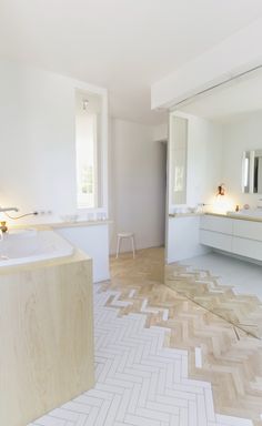 an empty bathroom with white walls and wood flooring on the floor, along with two sinks