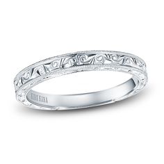 a white gold wedding band with intricate engraving on the sides and an engraved design in the middle