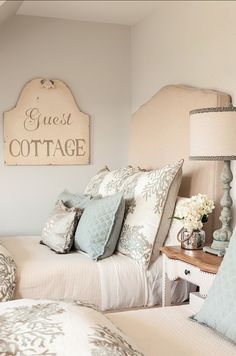 a bed room with two beds and pillows on top of each other in front of a sign that says guest cottage