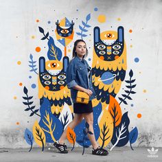 a woman is walking in front of a wall with an owl mural on the side