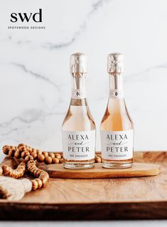 two bottles of wine sitting on top of a wooden cutting board next to pretzels