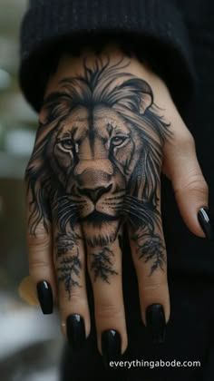 a woman's hand with a lion tattoo on it and black nails, holding onto the palm of her left hand