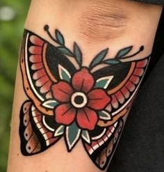 a woman's arm with a tattoo on it that has a red flower and green leaves