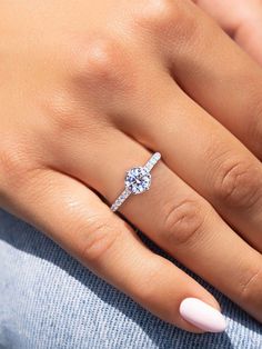 a woman's hand with a diamond ring on her finger and pink nail polish