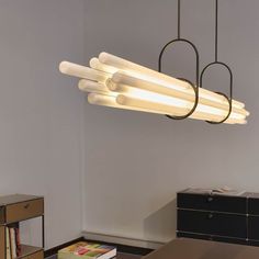 a light fixture hanging from the ceiling in a room with a table and bookcase