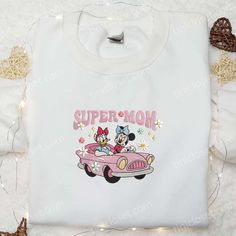 Super Mom Minnie And Daisy Embroidered Shirt, Disney Characters Embroidered Hoodie, Best Mother’s Day Gift Idea Welcome to Tinicloset, your enchanted wardrobe oasis where every garment is a canvas of charm and every stitch is a testament to love and creativity! Nestled within our virtual boutique is a treasure trove of custom embroidered apparel designed to sprinkle a little extra magic into your everyday wardrobe. From adorable shirts to snugly sweatshirts and everything in between, we&#8 Minnie And Daisy, Embroidered Apparel, Embroidered Clothes, All Things Cute, Best Mother, Super Mom, Embroidered Hoodie, Embroidered Sweatshirts, Couple Shirts