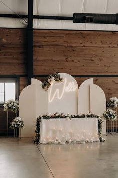 a sign that says we are surrounded by candles and flowers in front of a wooden wall