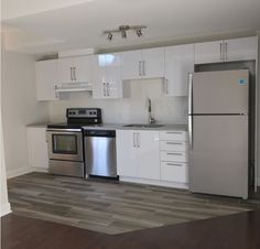 an empty kitchen with white cabinets and stainless steel appliances