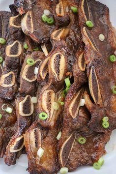 a white plate topped with meat covered in sauce and green onion garnishments