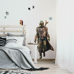 a bed room with a neatly made bed and a star wars character wall decal